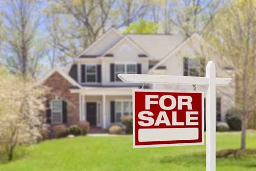 A realtor in District of Columbia shakes hands with clients in front of their new home 